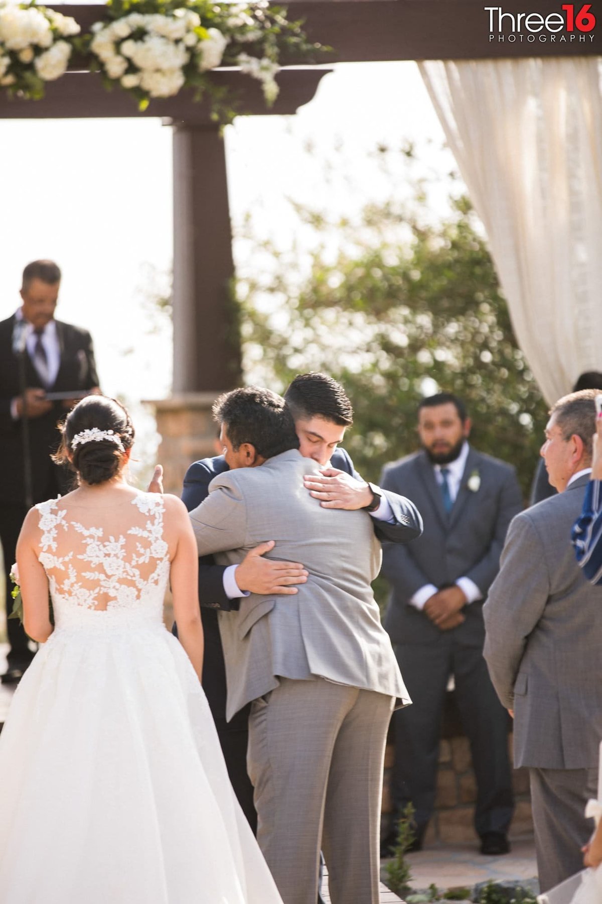 Father of the Bride hugs the Groom to be at the altar after handing his daughter to him