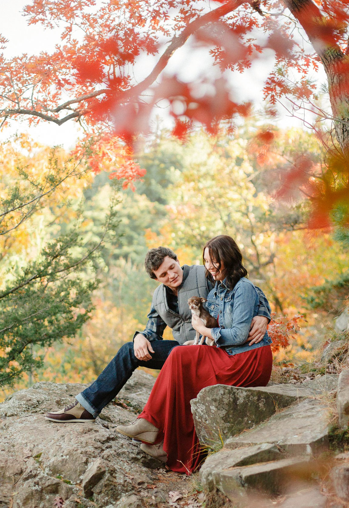 colored leaves of taylors falls state park with engaged couple and tiny dog