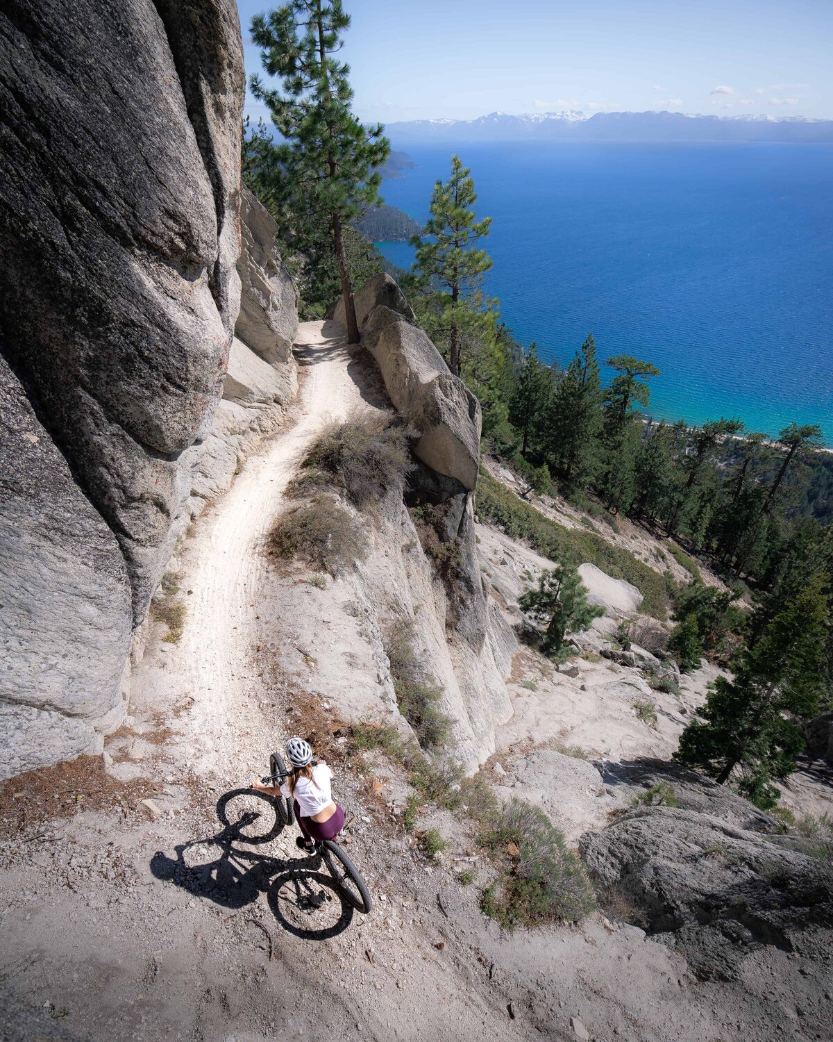 Woman walking up the side of a mountain with a bike at Lake Tahoe