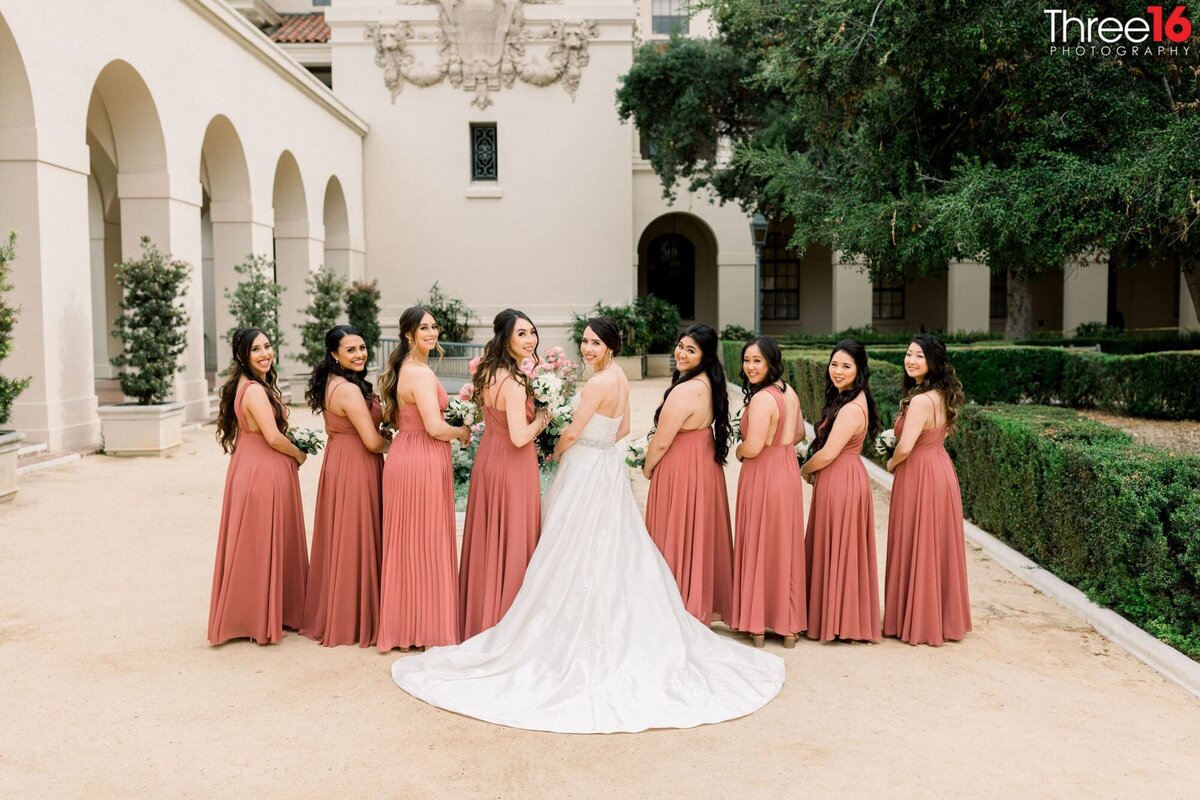 Bride and her Bridesmaids turn and look back at the wedding photographer