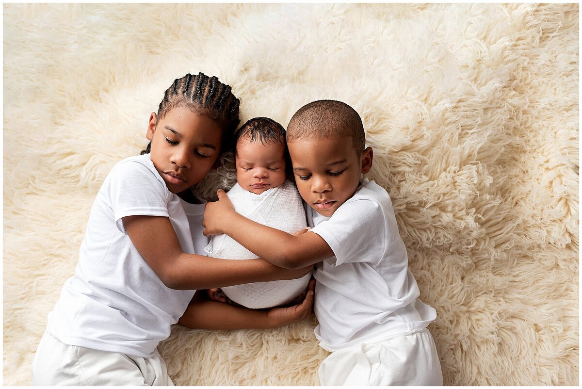 A bond that lasts a lifetime: Siblings holding their baby brother in their arms.