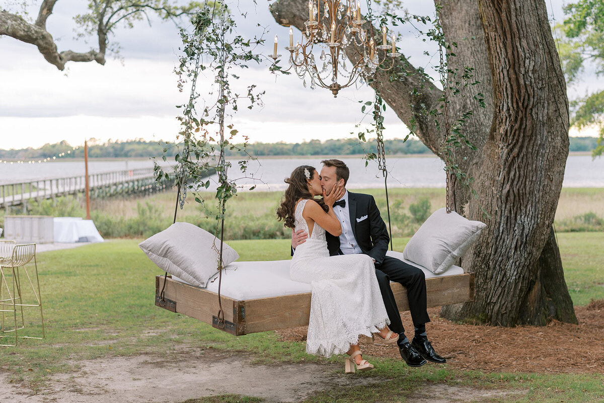 bride and groom sit on luxury swing at Lowndes Grove wedding venue