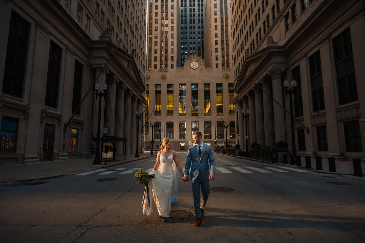 Bride and groom walk in front of the Chicago Board of Trade