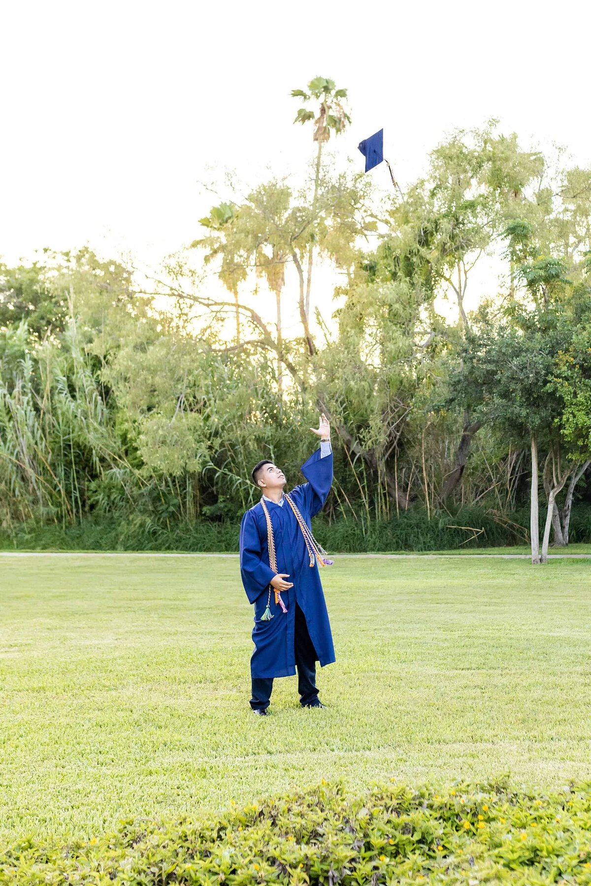 Senior in blue cap and gown tossing cap