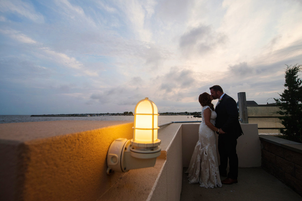 photo of bride and groom kissing on the rooftop deck from wedding reception at Lombardi's on the Bay