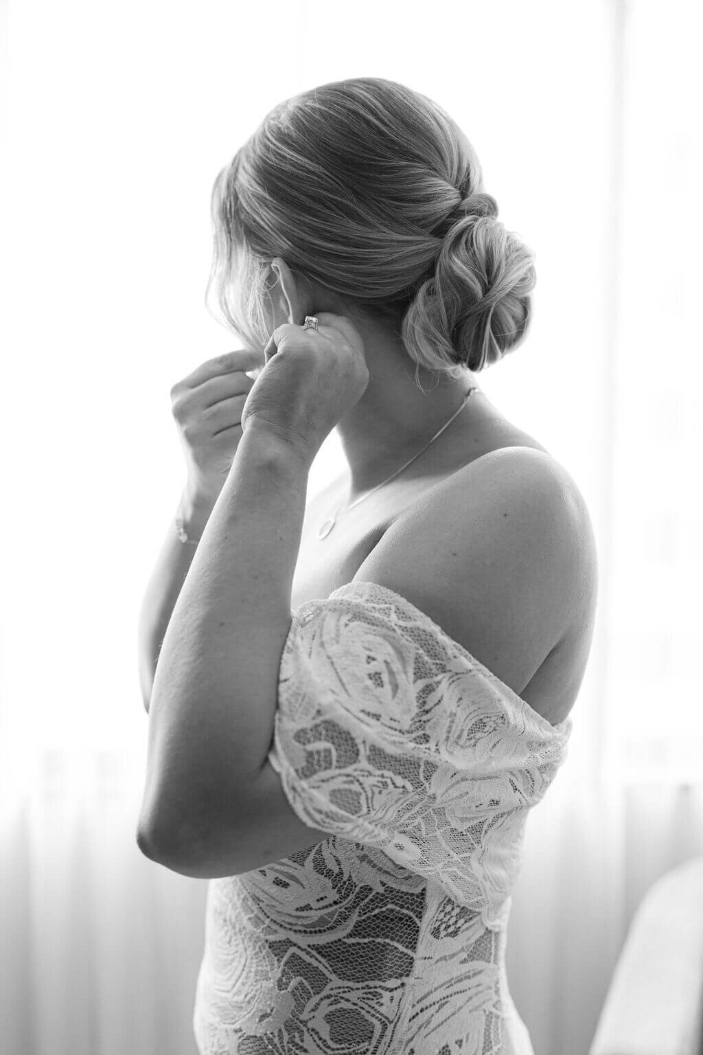 Stunning black and white image of bride putting on earrings in her DC bridal suite