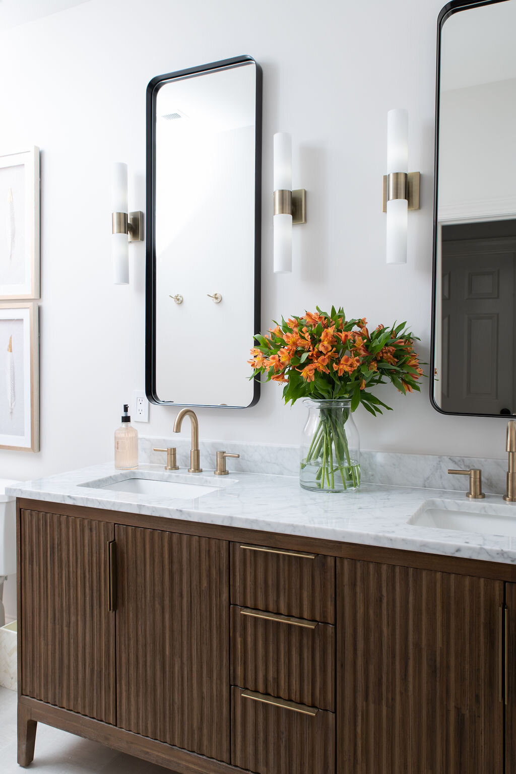 double sinks with white marble countertops and brown cabinetry