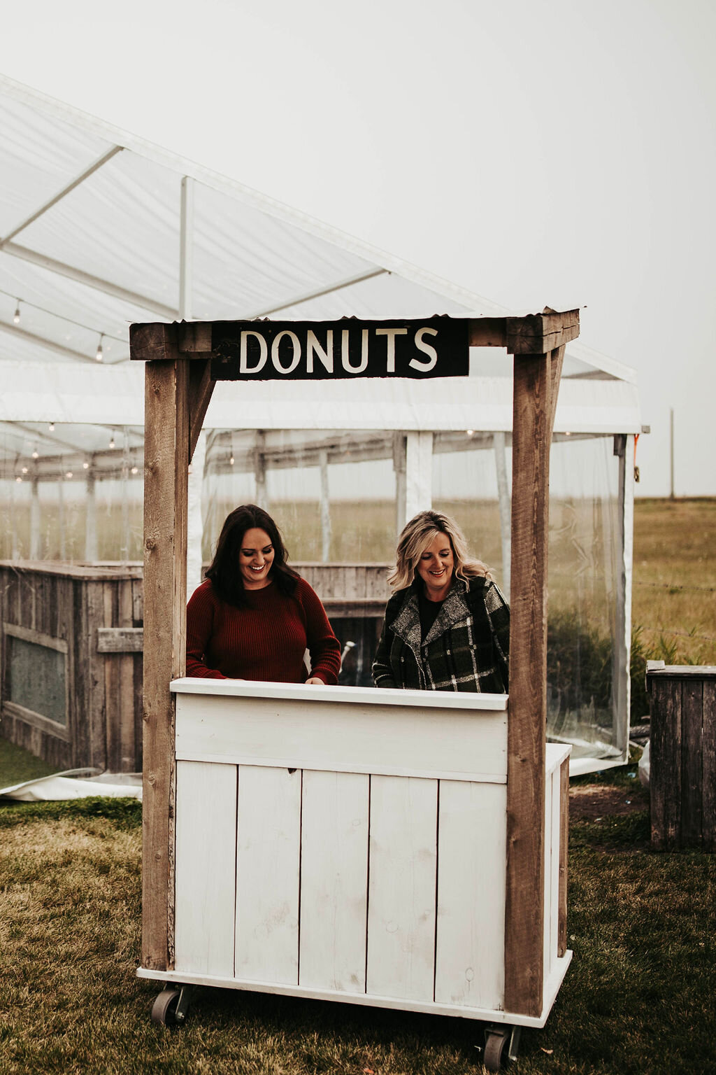 two women standing at a donut stand