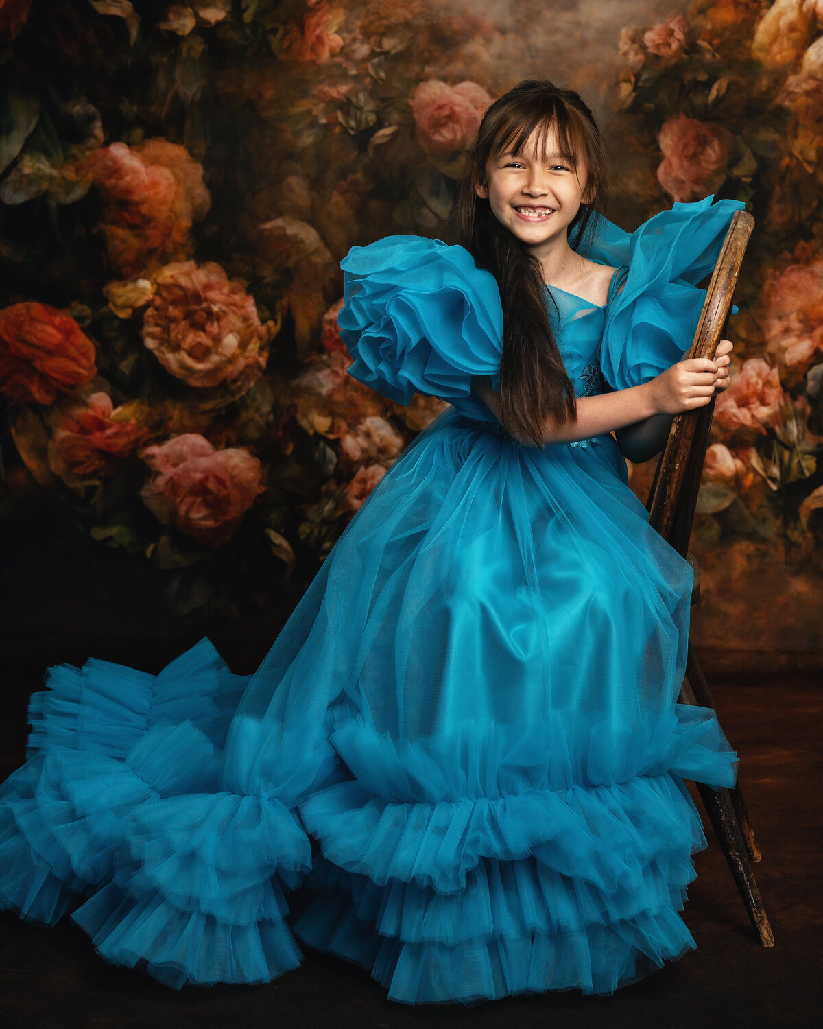 Pure magic in a turquoise ball gown! This stunning fine art portrait captures childhood joy with designer wardrobe, dramatic floral backdrop, and that priceless smile. AMM Fine Art Studio creates heirloom-quality children's portraits with luxury gowns, professional styling, and an unforgettable experience. Serving Kirkland and Seattle.
