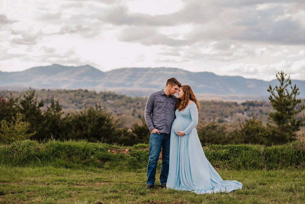 photo of man and pregnant woman in front of mountains