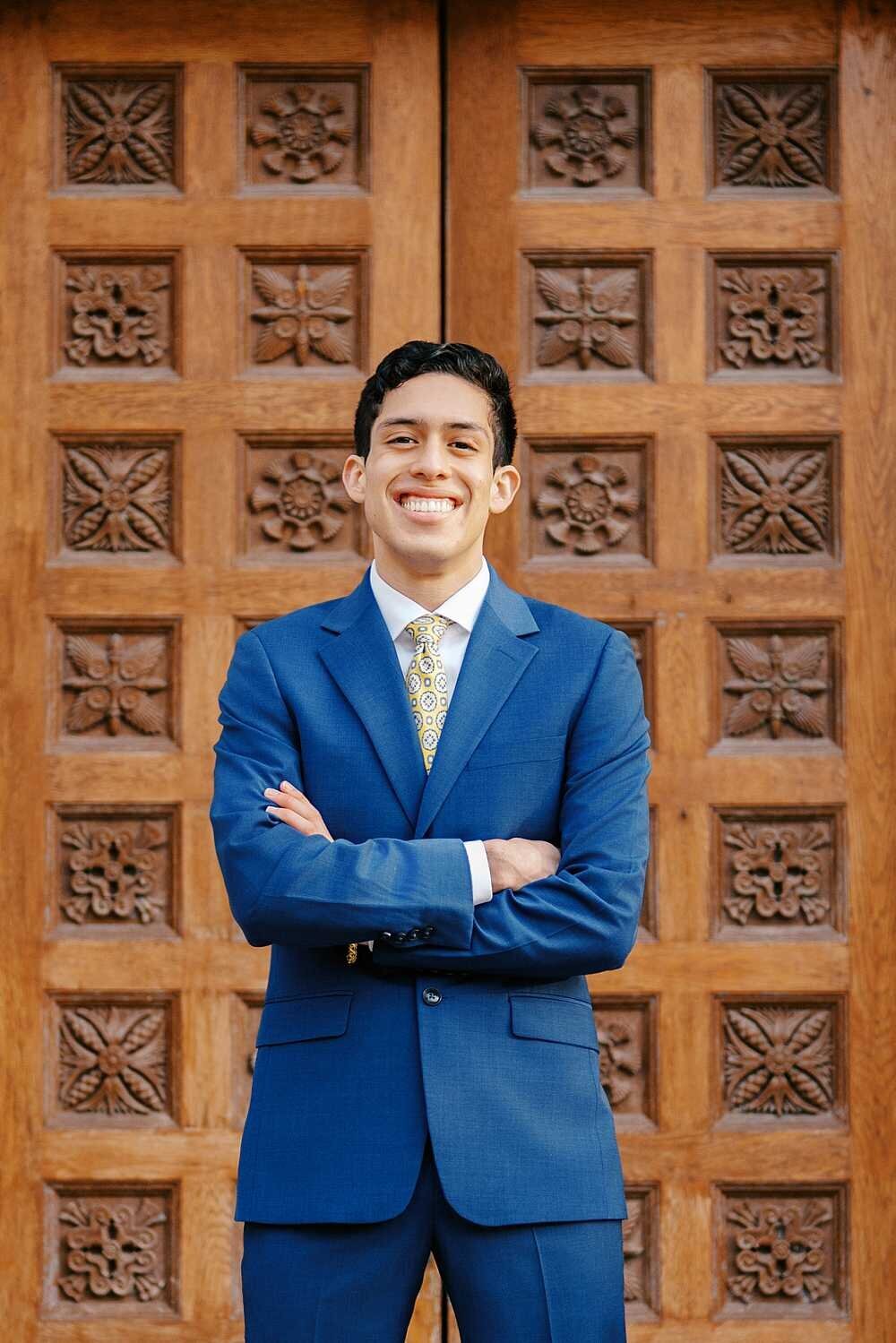 graduating Senior guy wearing a blue suit on his university campus
