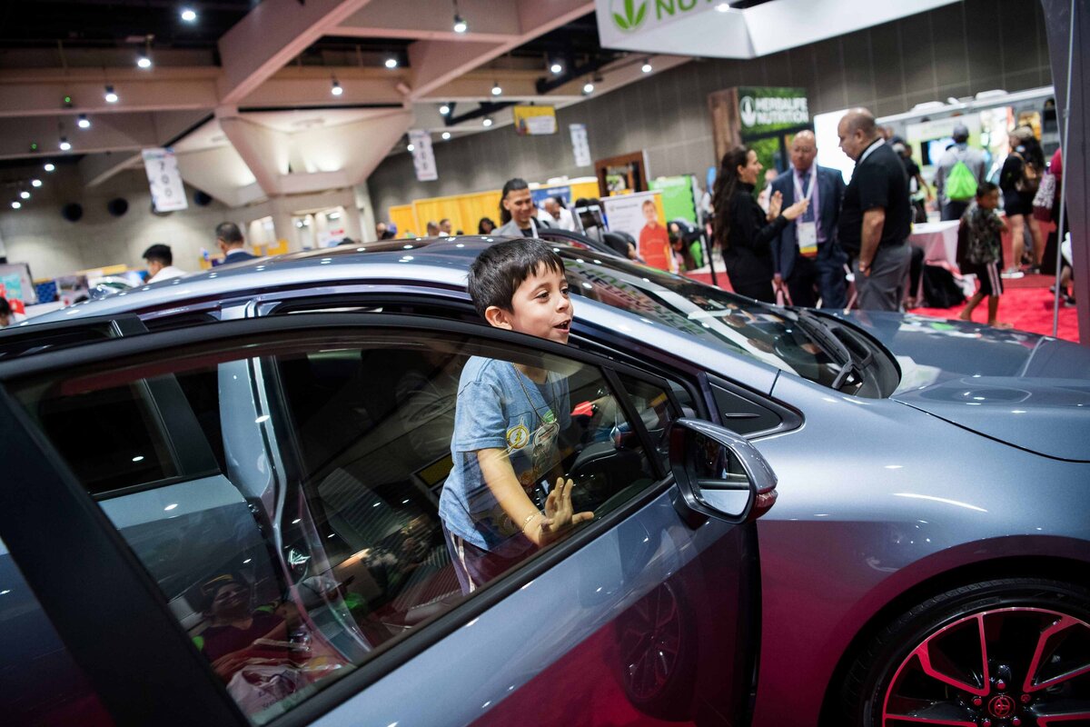 A boy looks excited as he peers out from a Toyota Camry at San Diego Convention Center