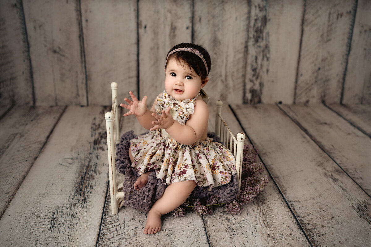 baby girl sitting in bed with floral dress photo by for the love of photography lansing