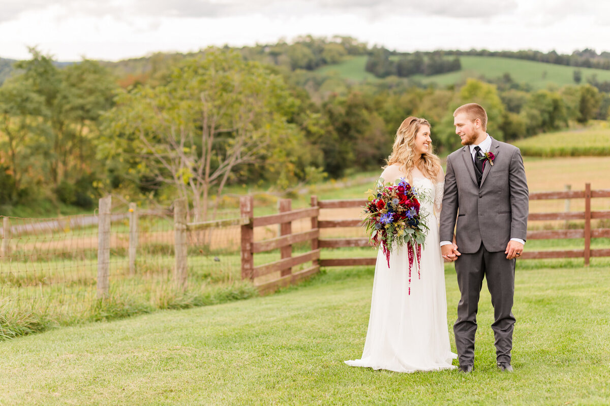A newly married couple walk in the field at the barn at kline's mill