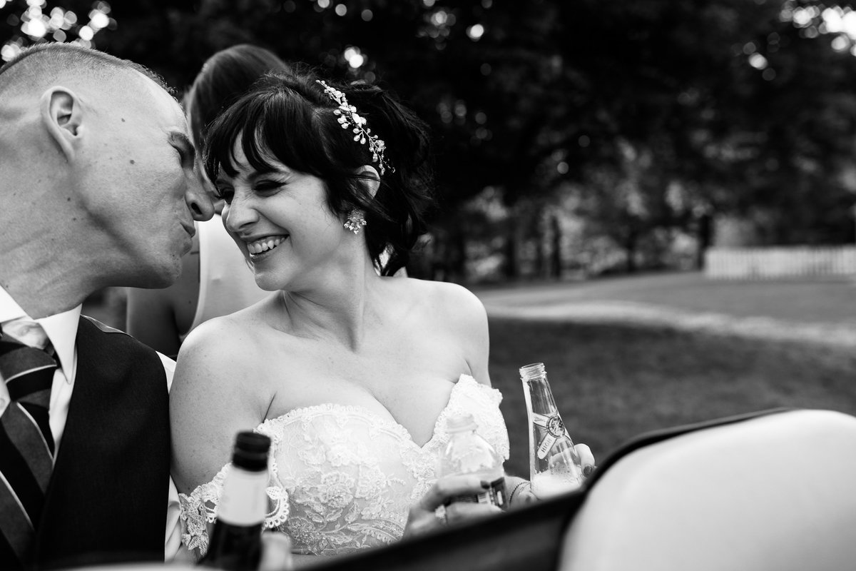 Groom steals a kiss from the bride on golf cart