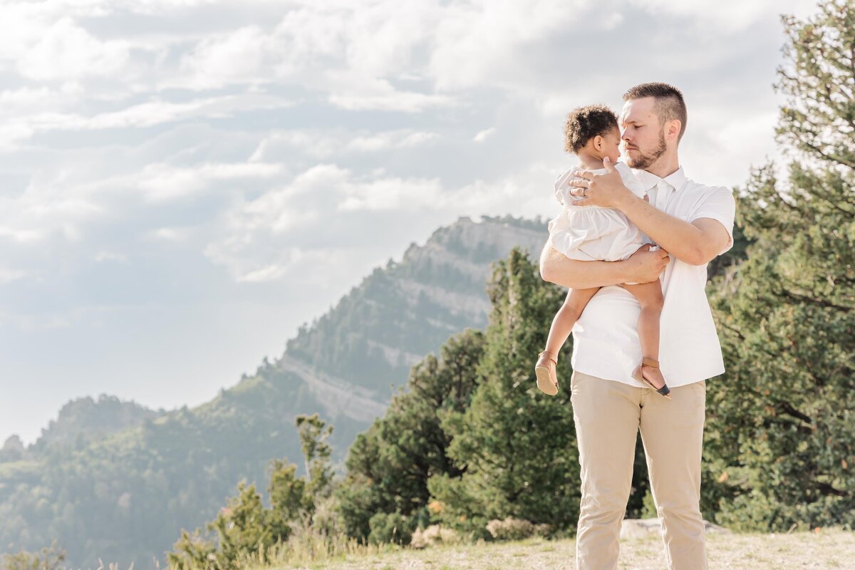 Daddy holding daughter with mountains in the background