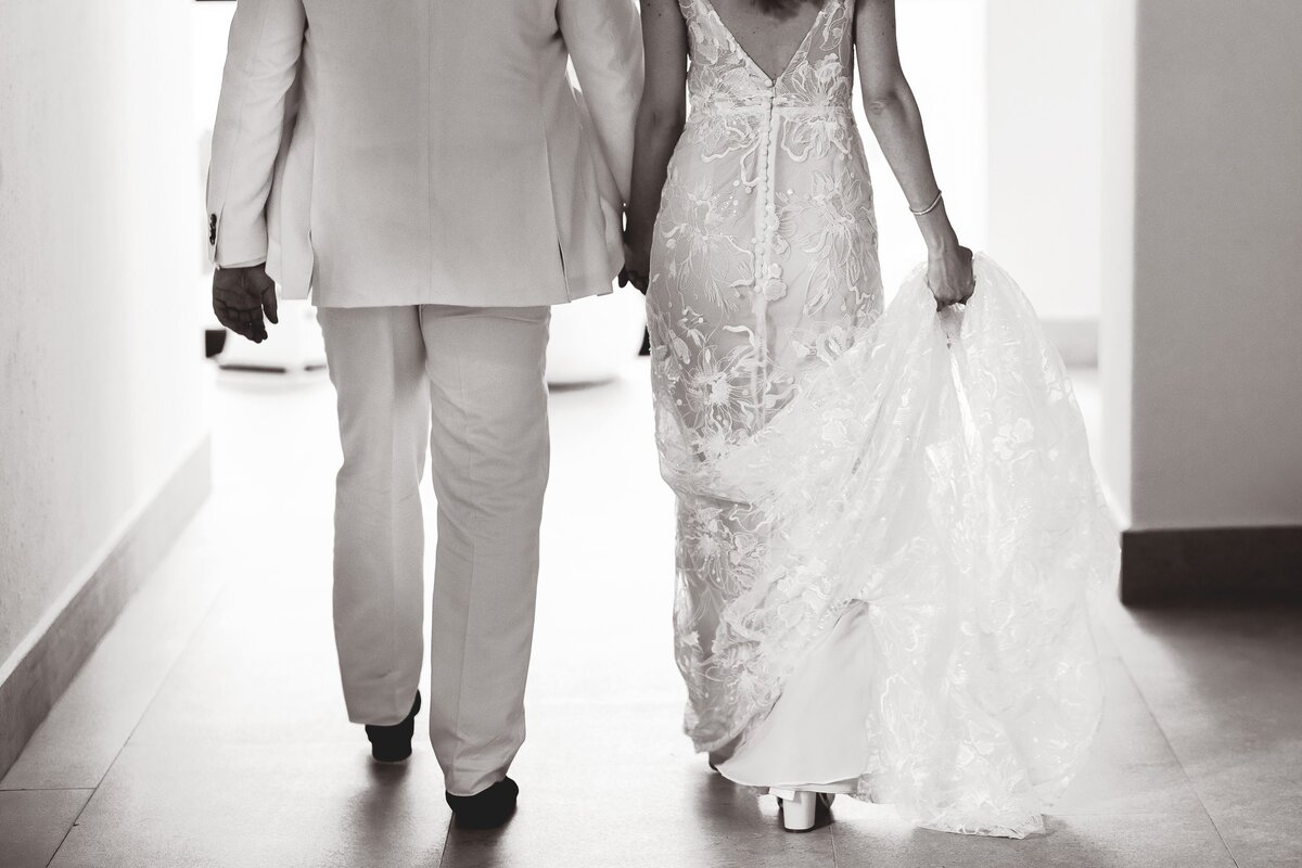Black and white of bride and groom holding hands and walking away at Riviera Maya wedding