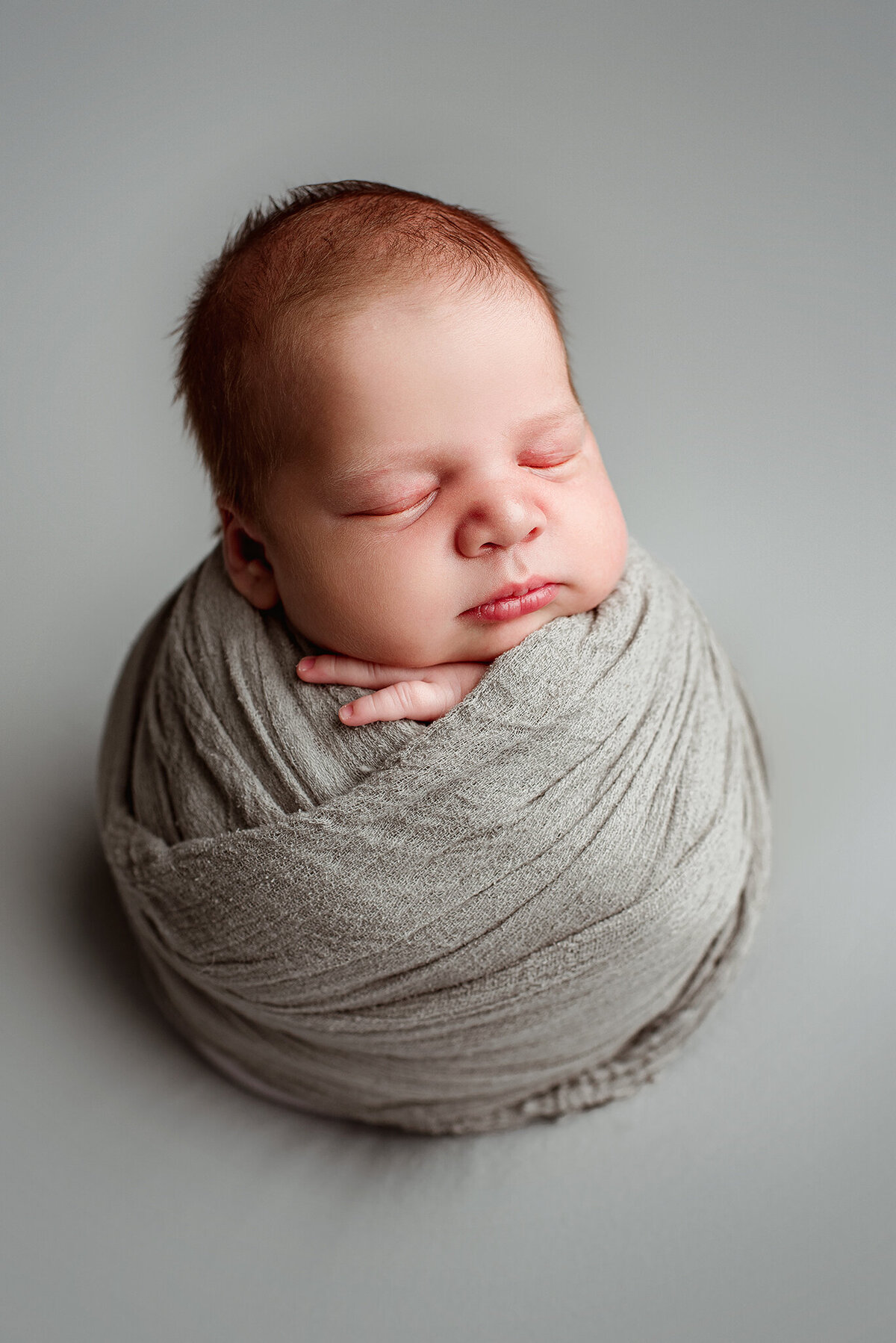 In home studio newborn portrait of baby boy wrapped in gray in St. Johns, FL.