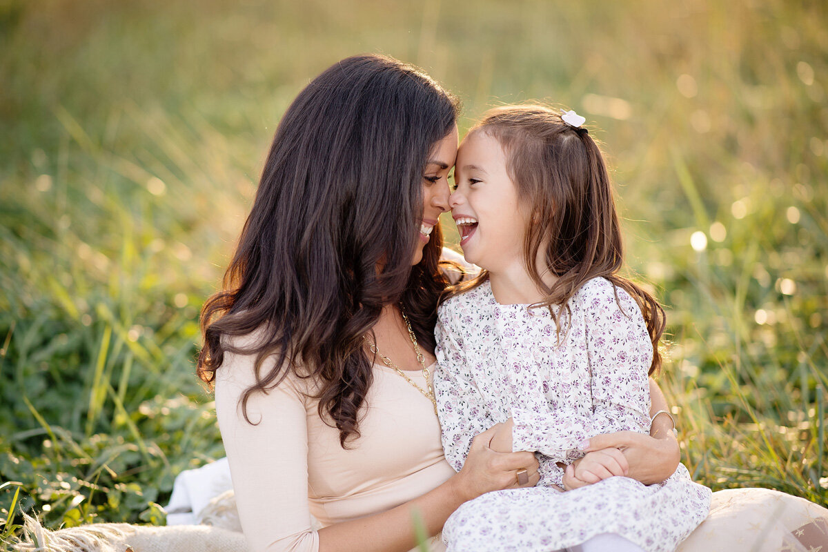 Family session of little girl and mother sitting in a field