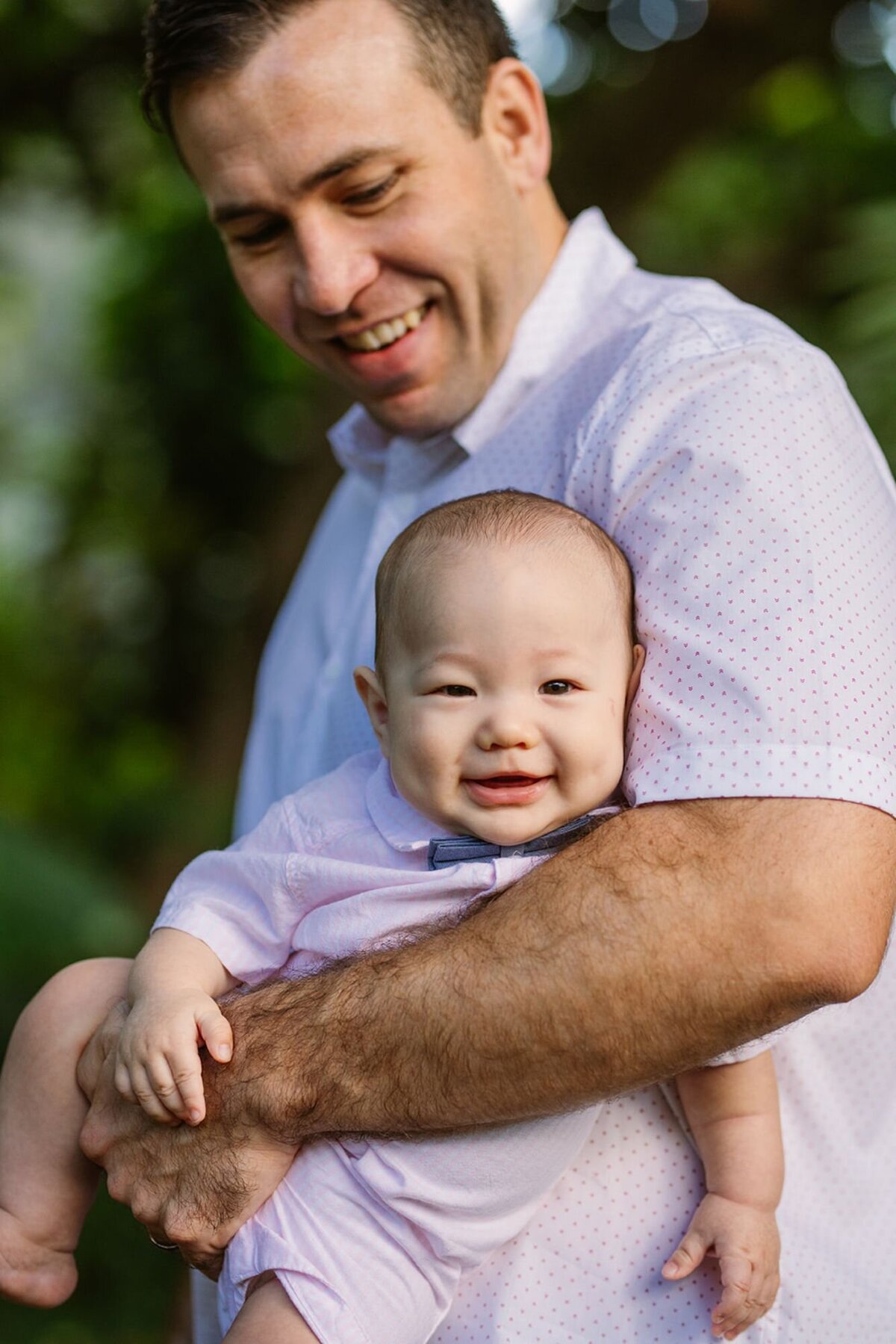 dad holds a laughing baby on his forearm