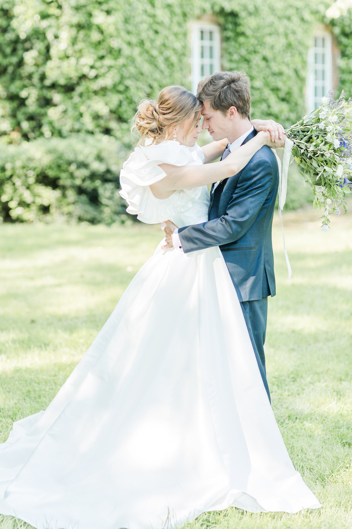 Bride and groom share a casual embrace. Their heads are touching, the bride's arm's draped around the groom's neck and the groom's arms holding the small of the bride's back. Their foreheads touching. Captured by North Shore Boston Wedding photographer Lia Rose Weddings
