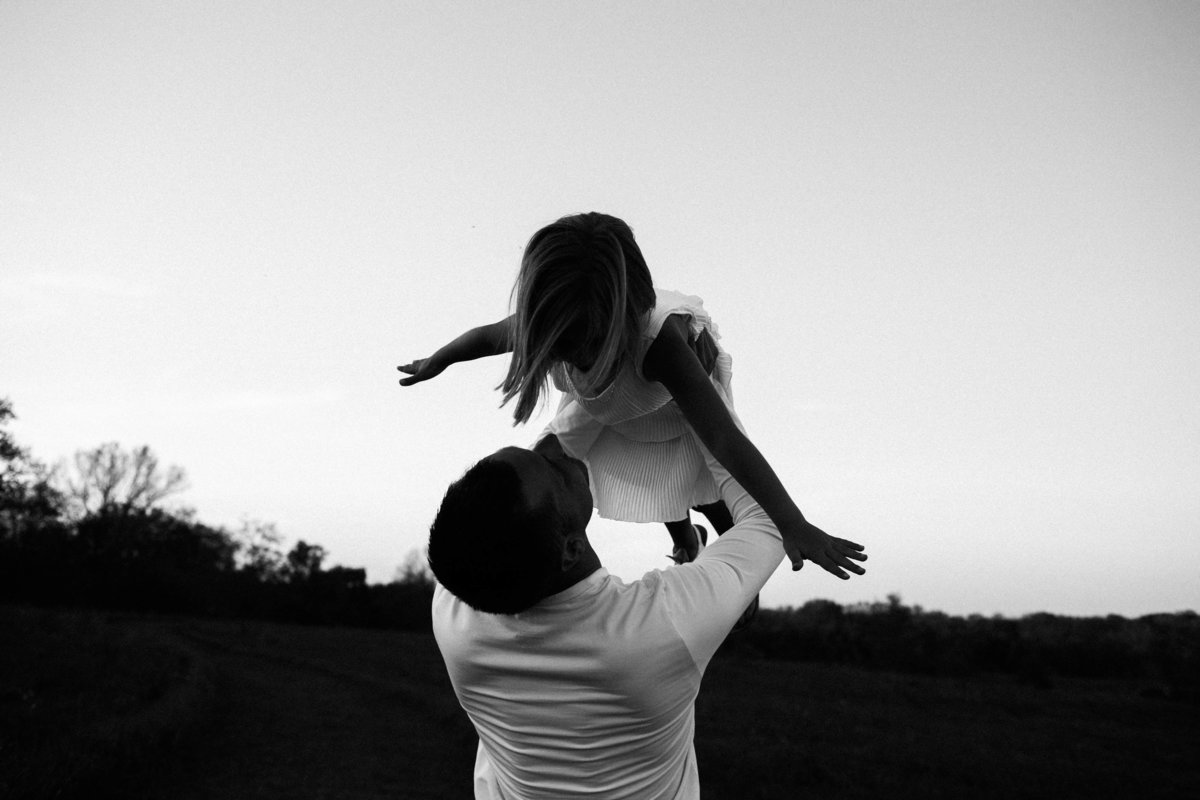 Dad holding daughter in air playing airplane during sunset session, Elle Baker Photography