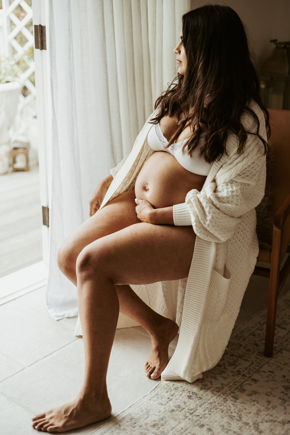 Pregnant mama in white underwear and robe posing in her chair to capture her pregnancy.