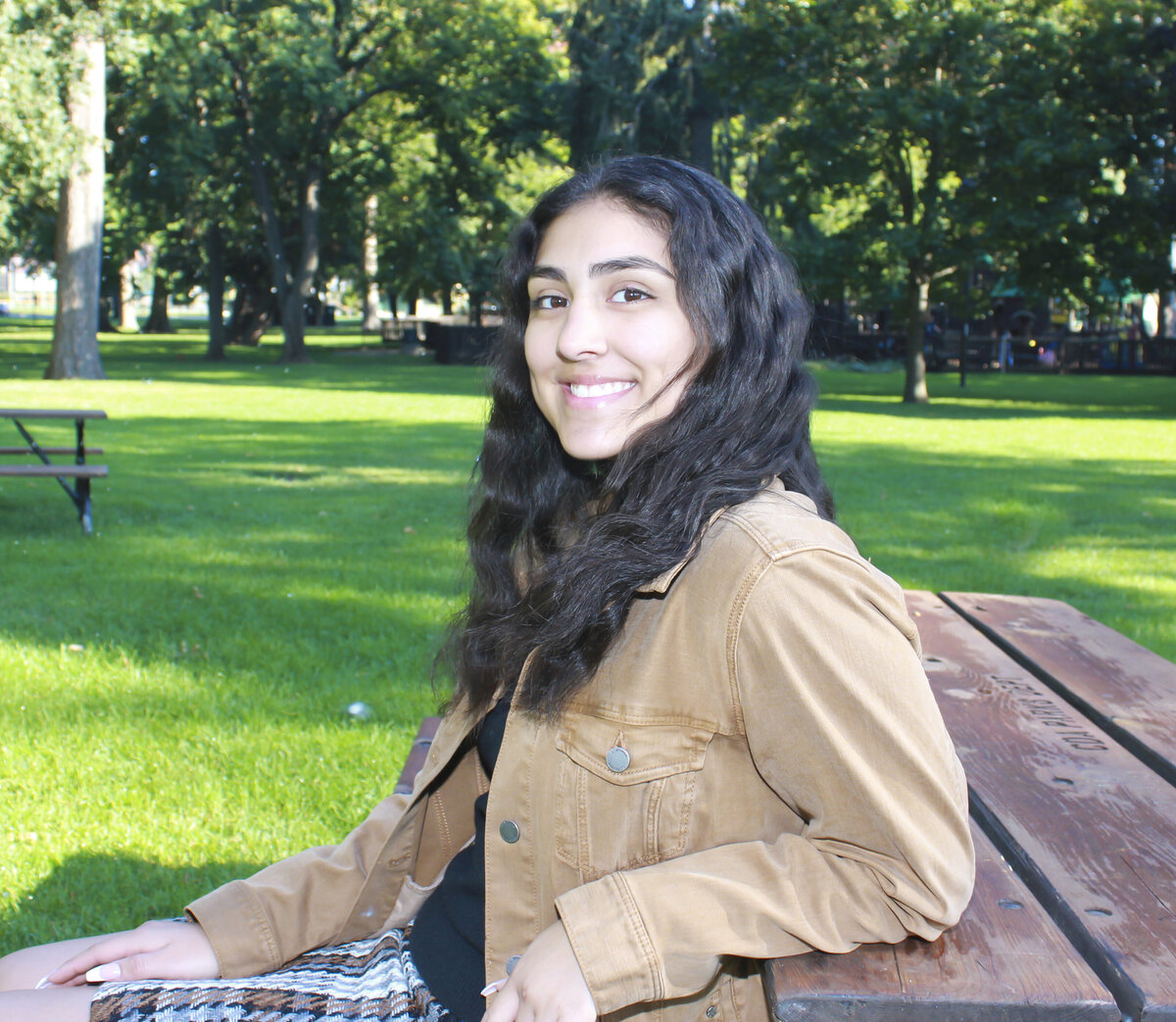 young lady sitting on bench at a park smiling