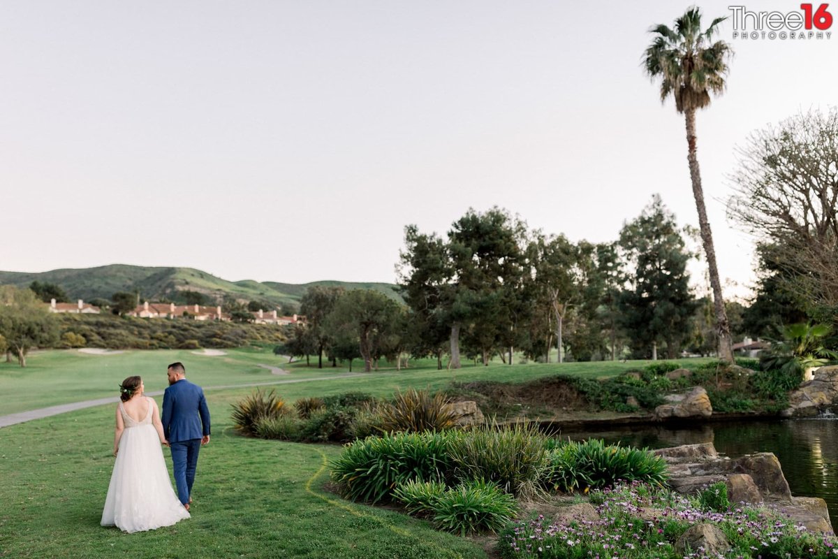 Bride and Groom go for a walk hand in hand along the San Juan Hills Golf Club