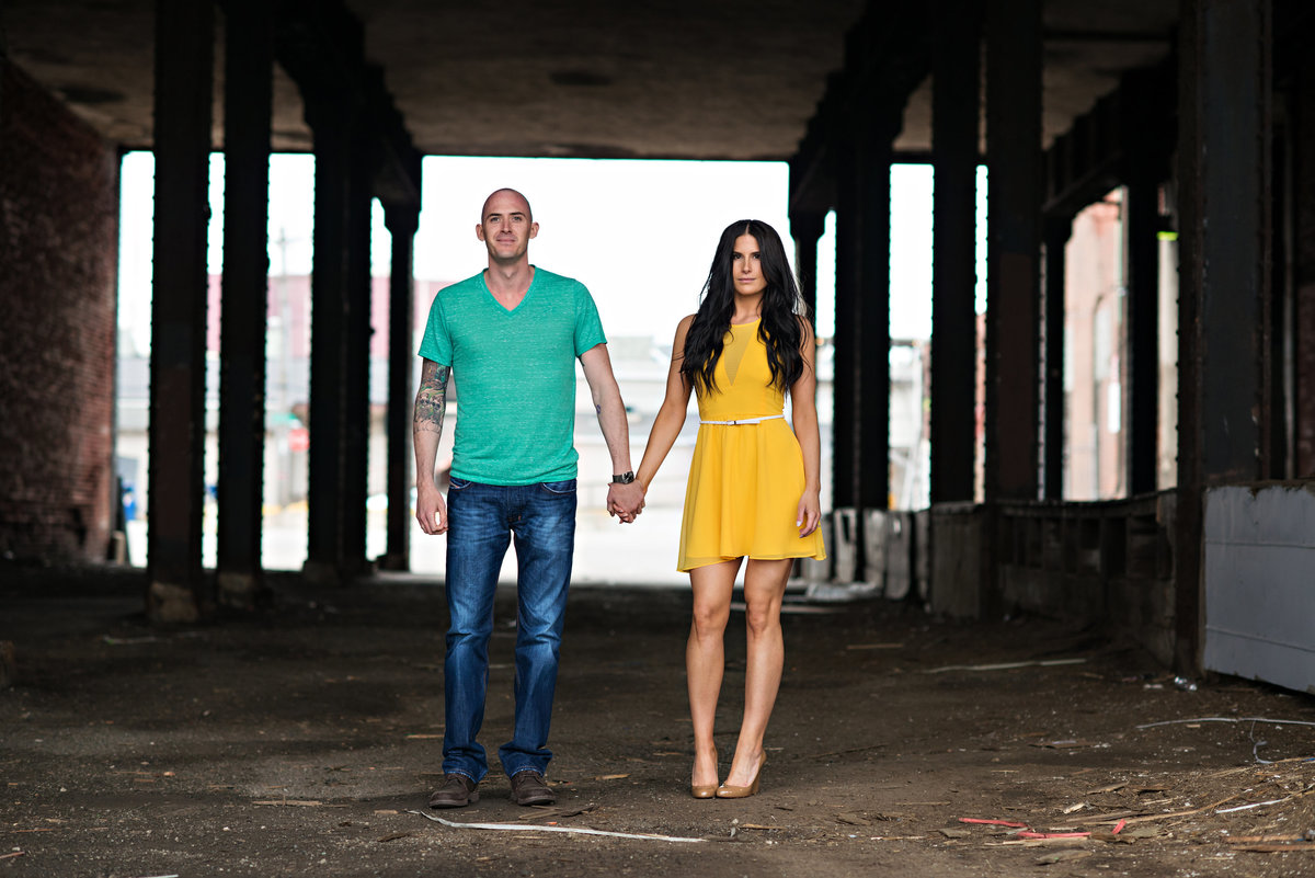 A sexy couple hold hands in the industrial part of old city philadelphia.