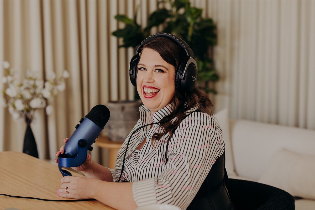 woman in headphones while sitting at a desk in front of a microphone