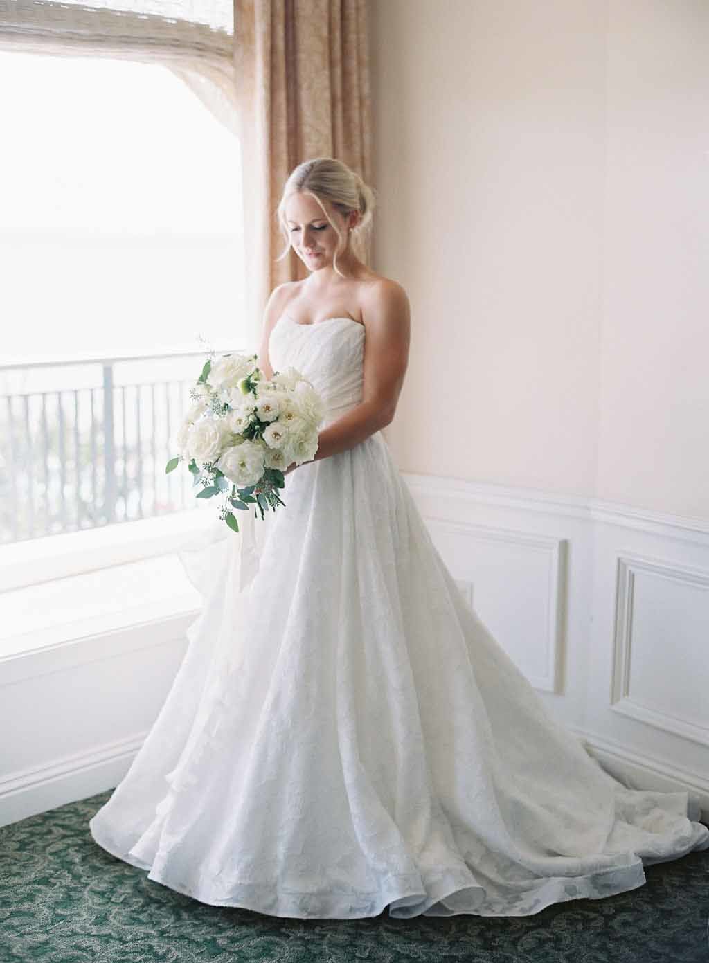 bride in long white trailing dress holding white bridal bouquet