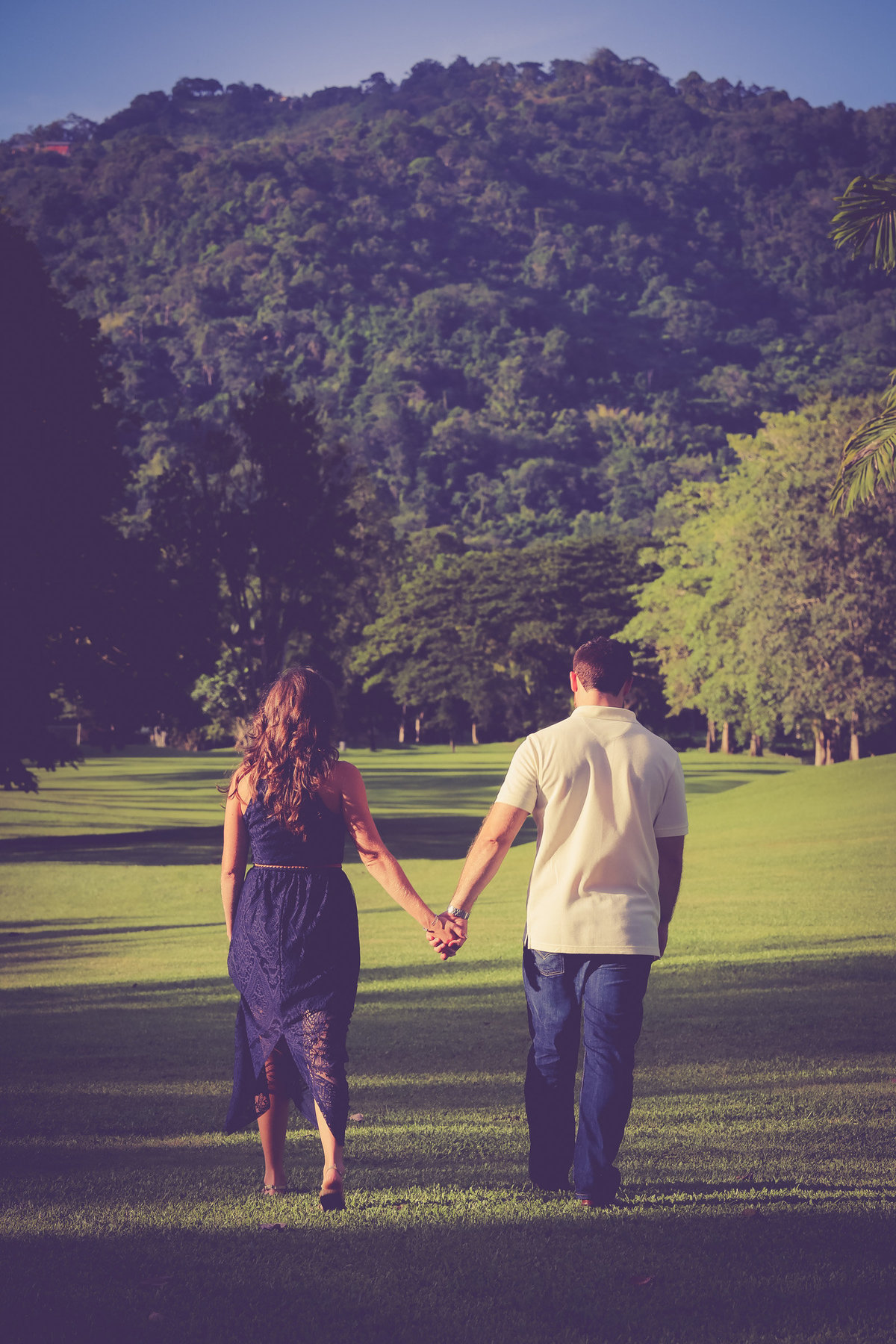 Couple walks away from camera while holding hands in outdoor engagement shoot. Photo by Ross Photography, Trinidad, W.I..