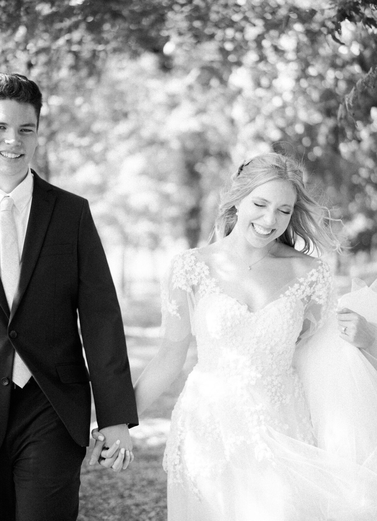 A bride and groom walk toward the camera while laughing in black and white by Huntsville wedding photographer, Kelsey Dawn Photography