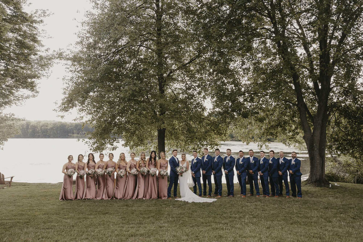 Full wedding party outside near a lake