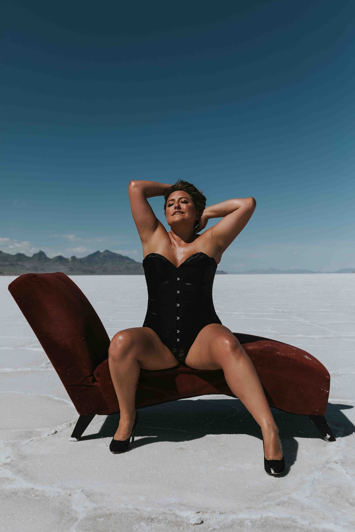 Woman posing on a red chaise lounge  on the middle of the Bonneville Salt Flats