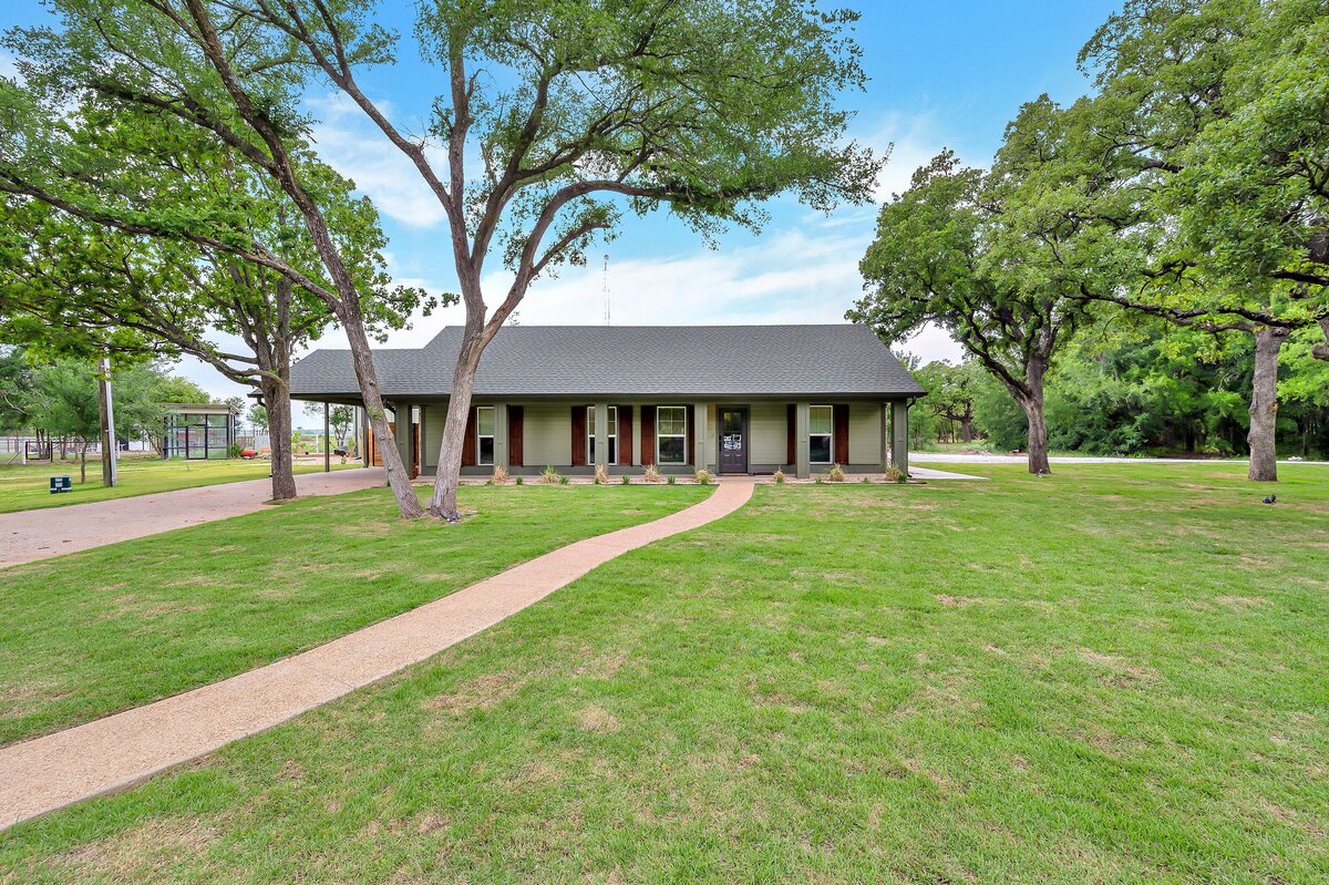 Front view with large yard of this three-bedroom, three-bathroom vacation rental home with free wifi, outdoor theater, hot tub, propane grill and private yard in Waco, TX.