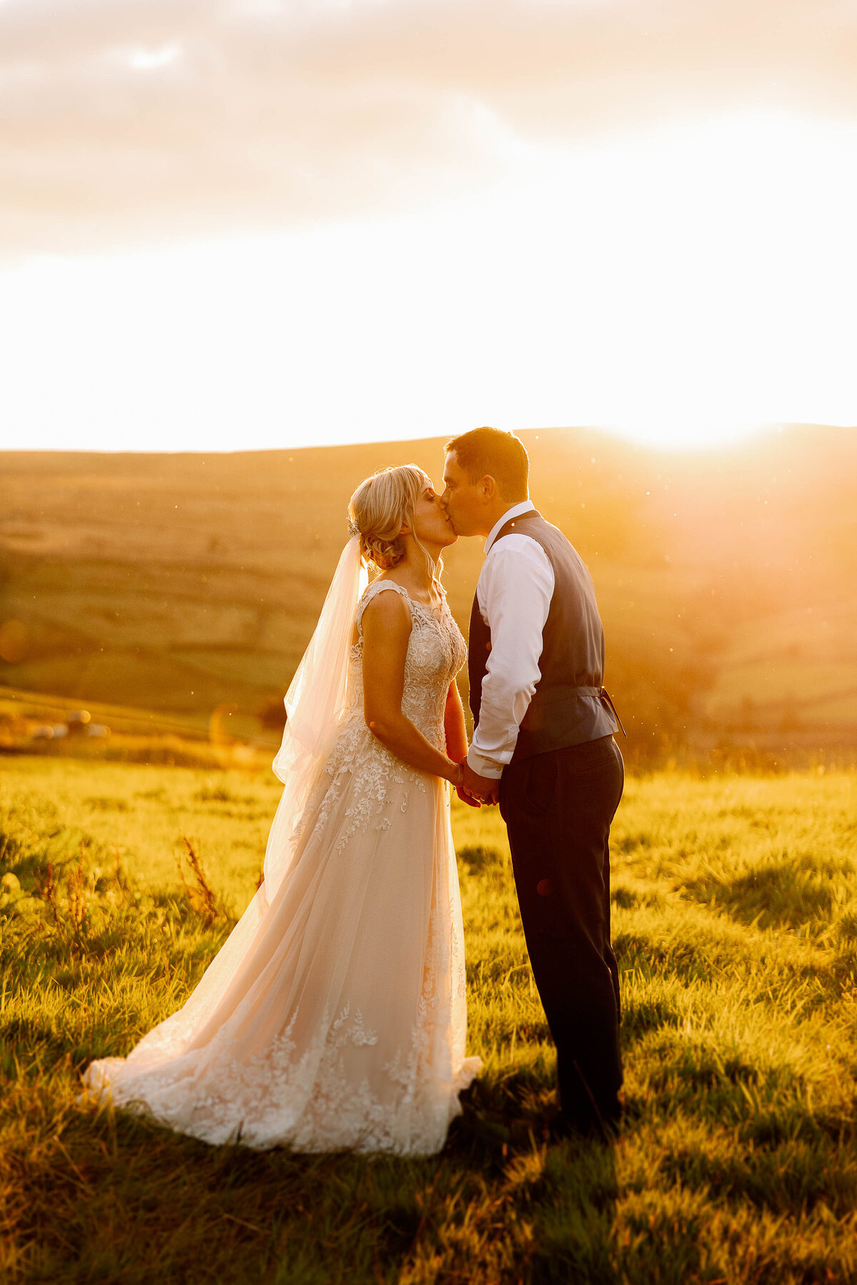 Bride and groom kissing at sunset on the moors above Haworth