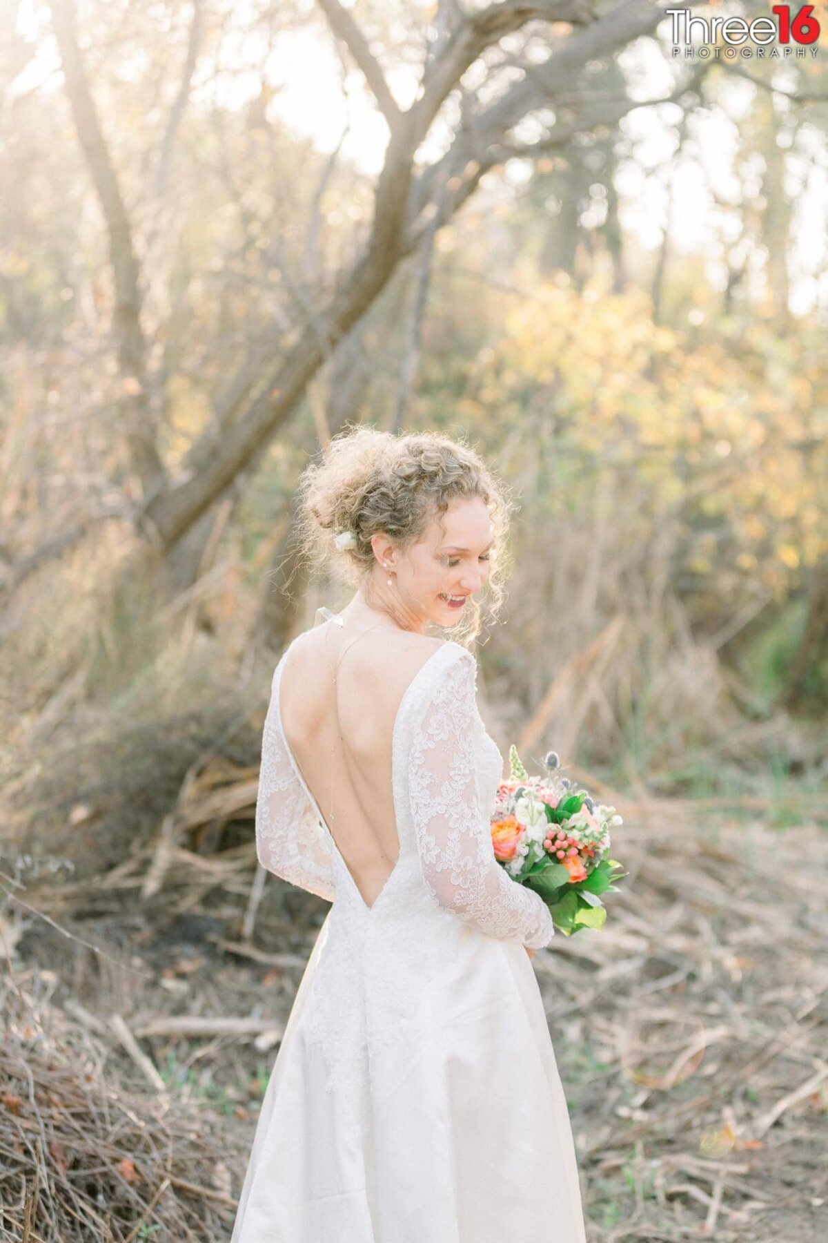 Bride poses with her back to the camera as she turns her head towards the wedding photographer