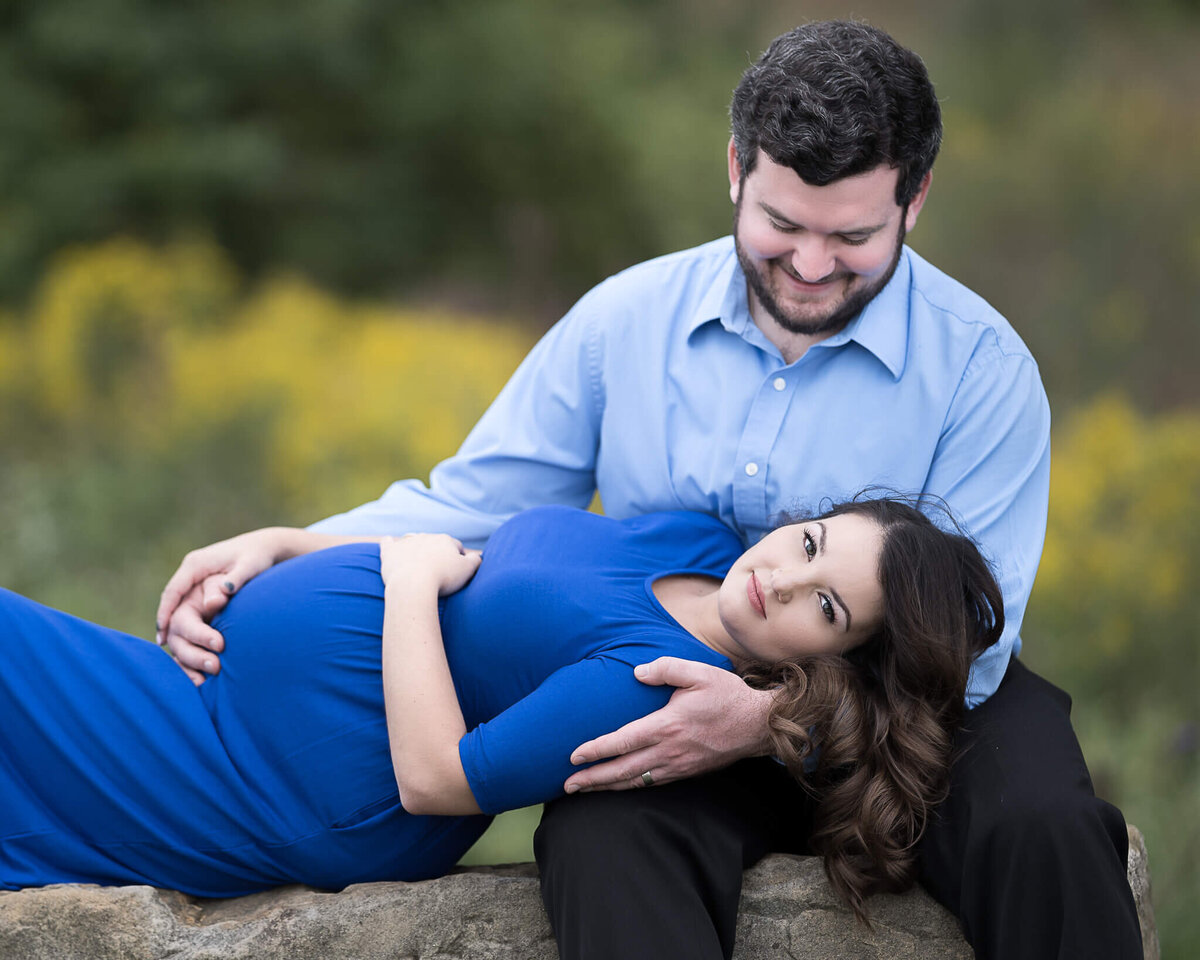 Maternity session at beautiful park mom in blue dress and dad in blue shirt.