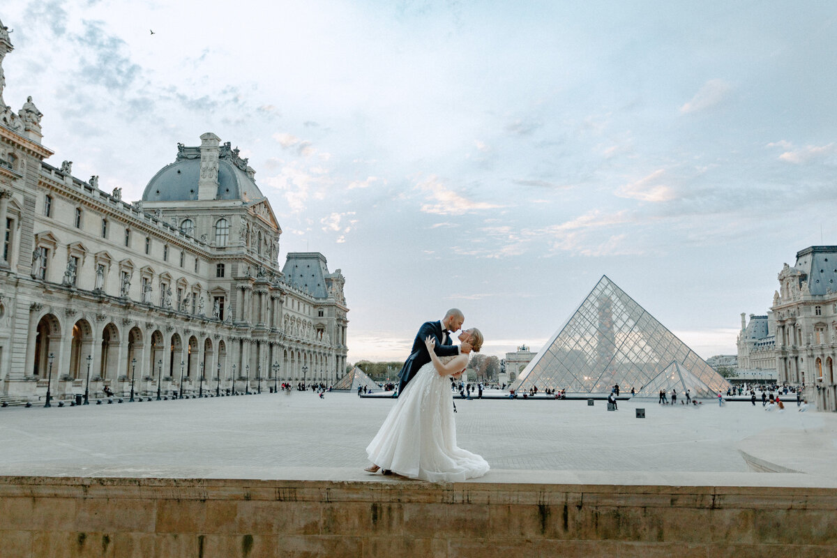 groom dipping bride back for photo session after eloping in paris at the louvre