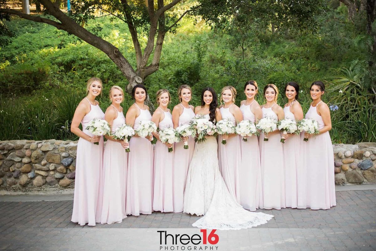 Bride poses with her 10 Bridesmaids wearing light pink