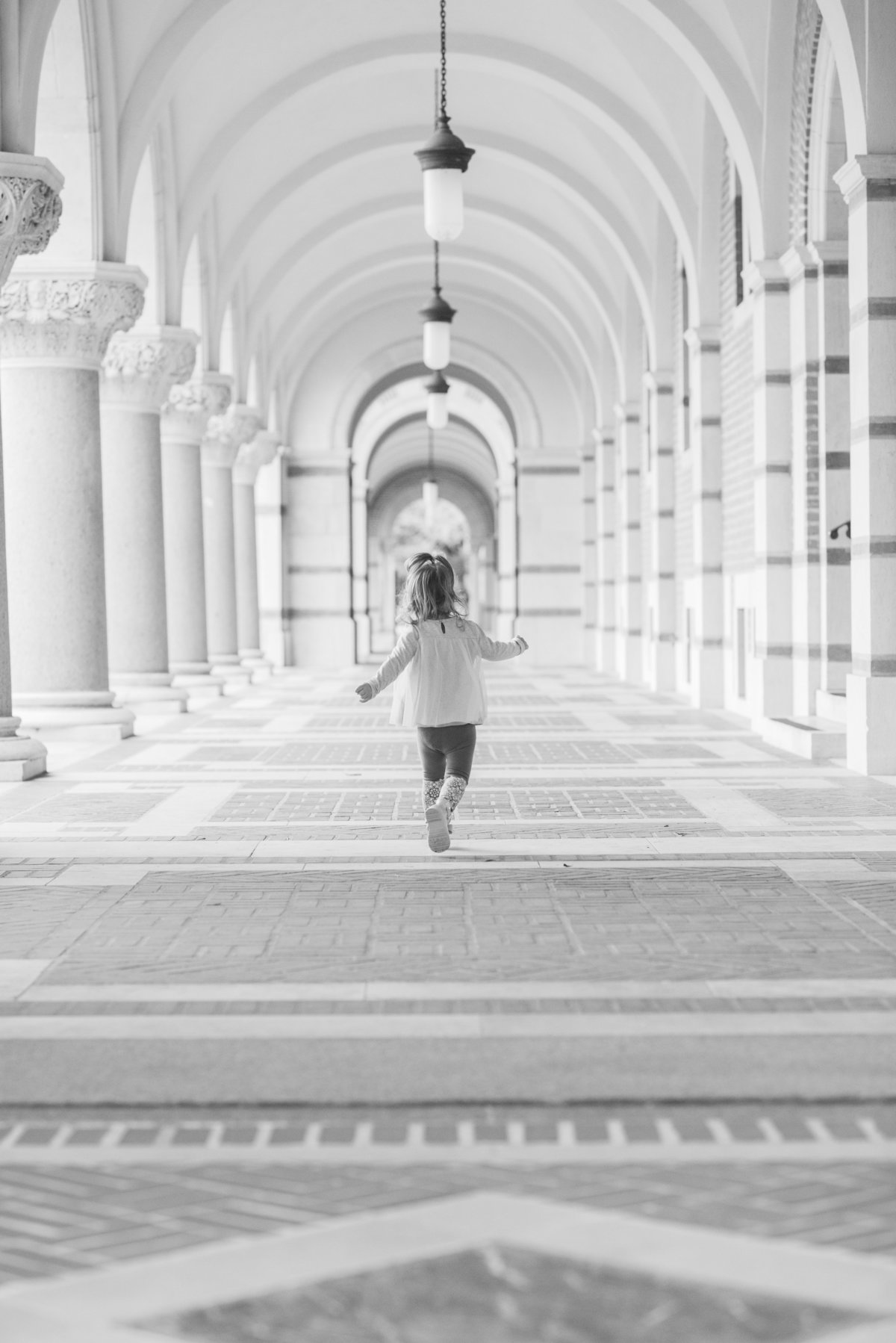 toddler girl running under arches on RIce University campus