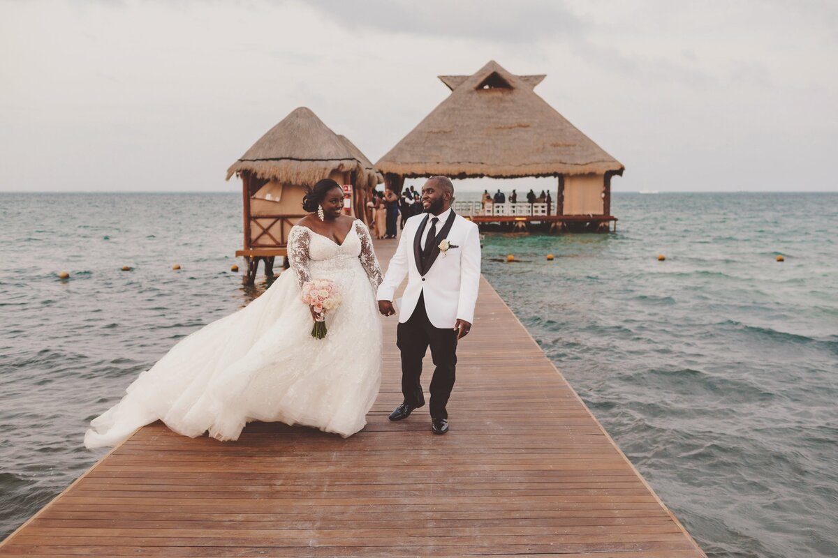 Bride and groom walk on dock at wedding in Cancun