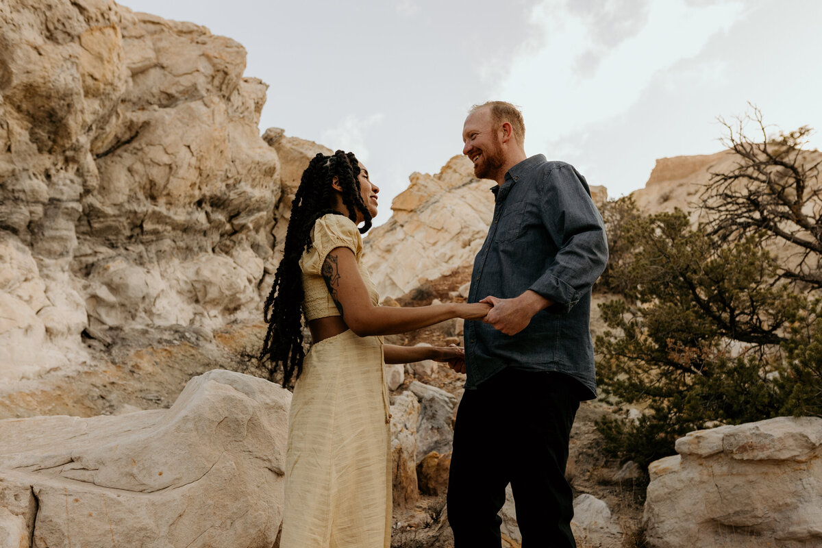 man and woman holding hands about to kiss in the desert