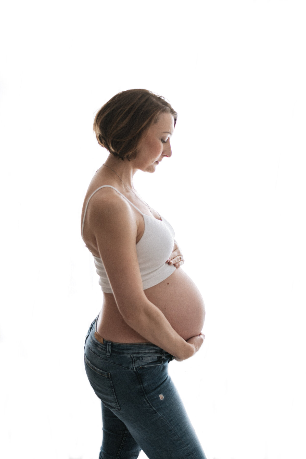 Mother holding pregnant bump on maternity photoshoot in Billingshurst