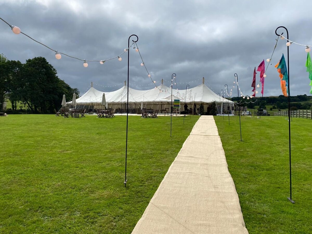 A long walkway with strings of light all the way down leading to a large pole marquee