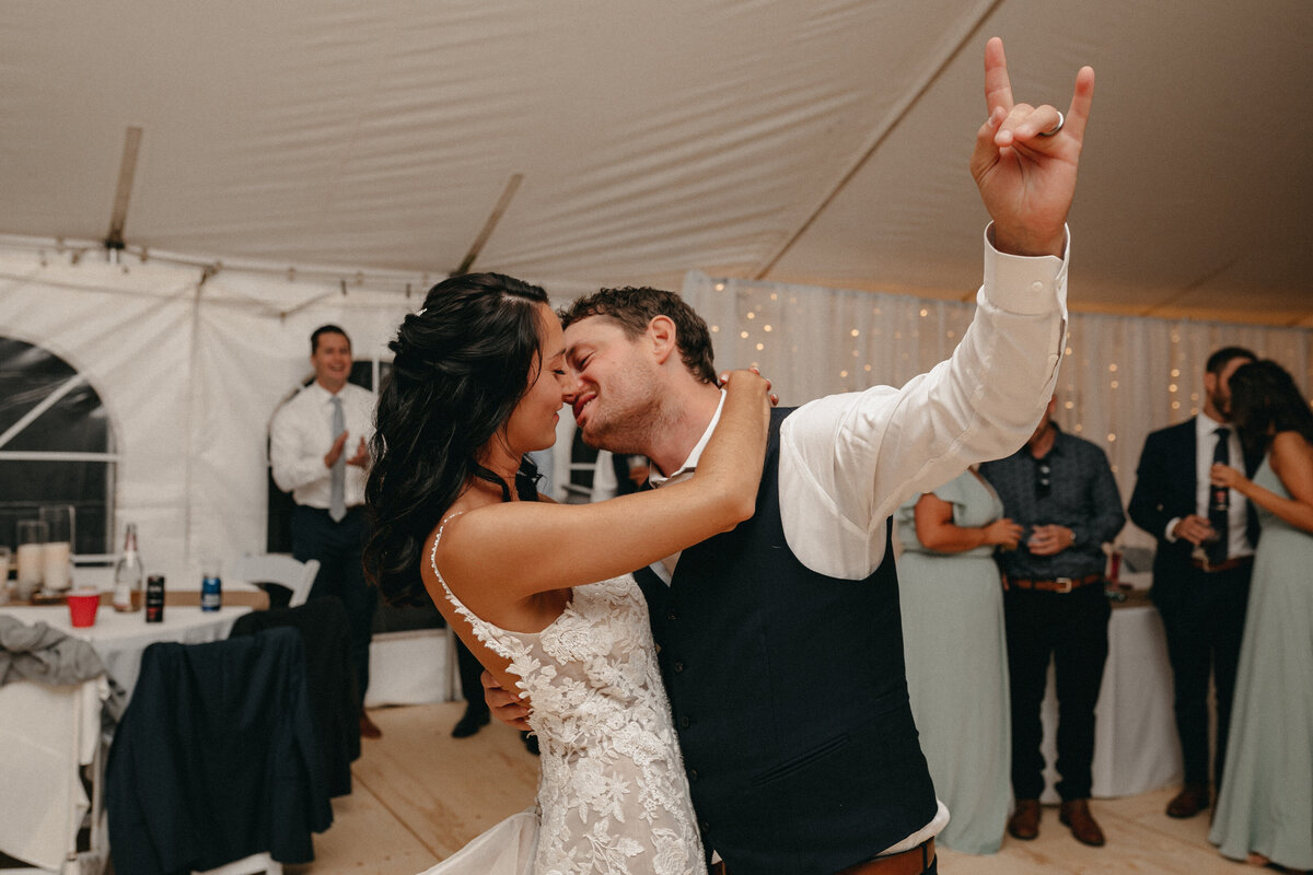 bride and groom kissing and groom has rock on hand sign