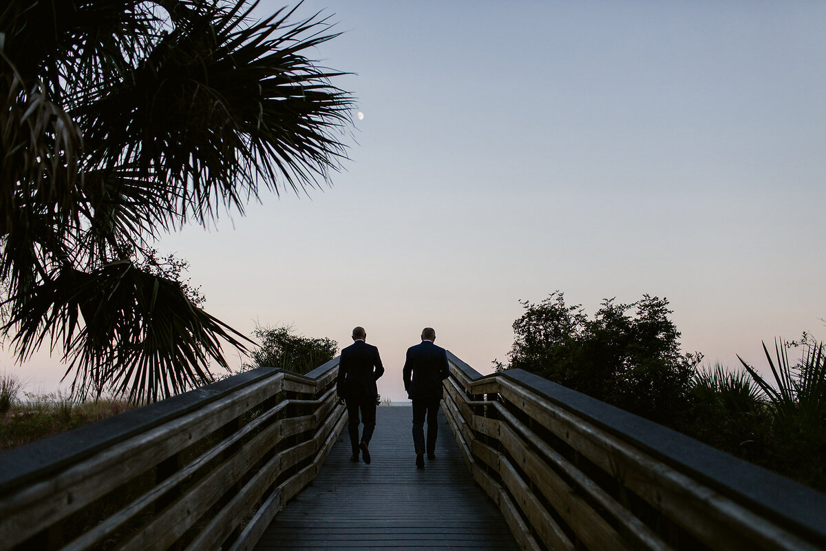 Grooms walking up a dock at sunset.