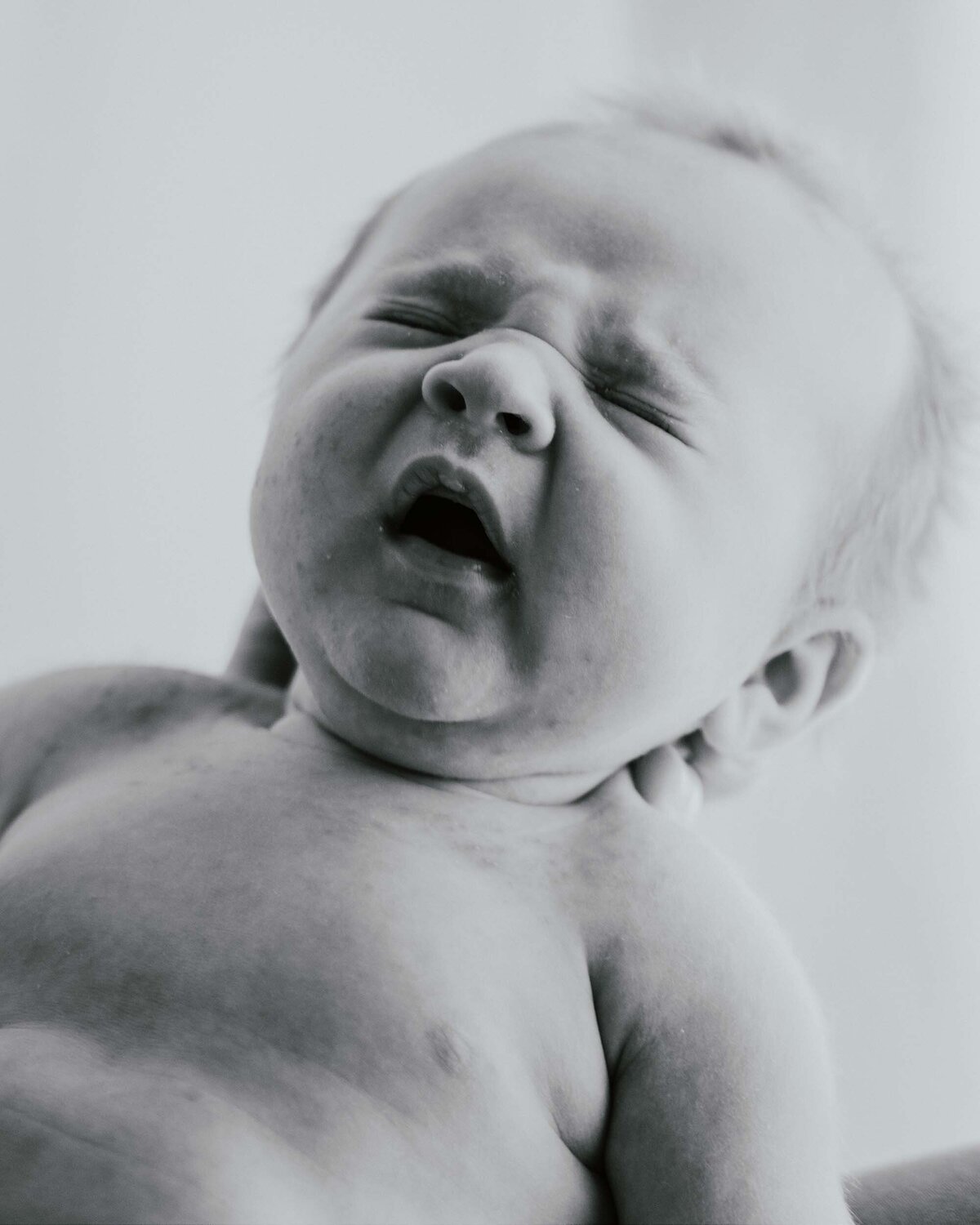 Maddie Rae Photography black and white of baby yawning and he has a scrunchie nose and eyes